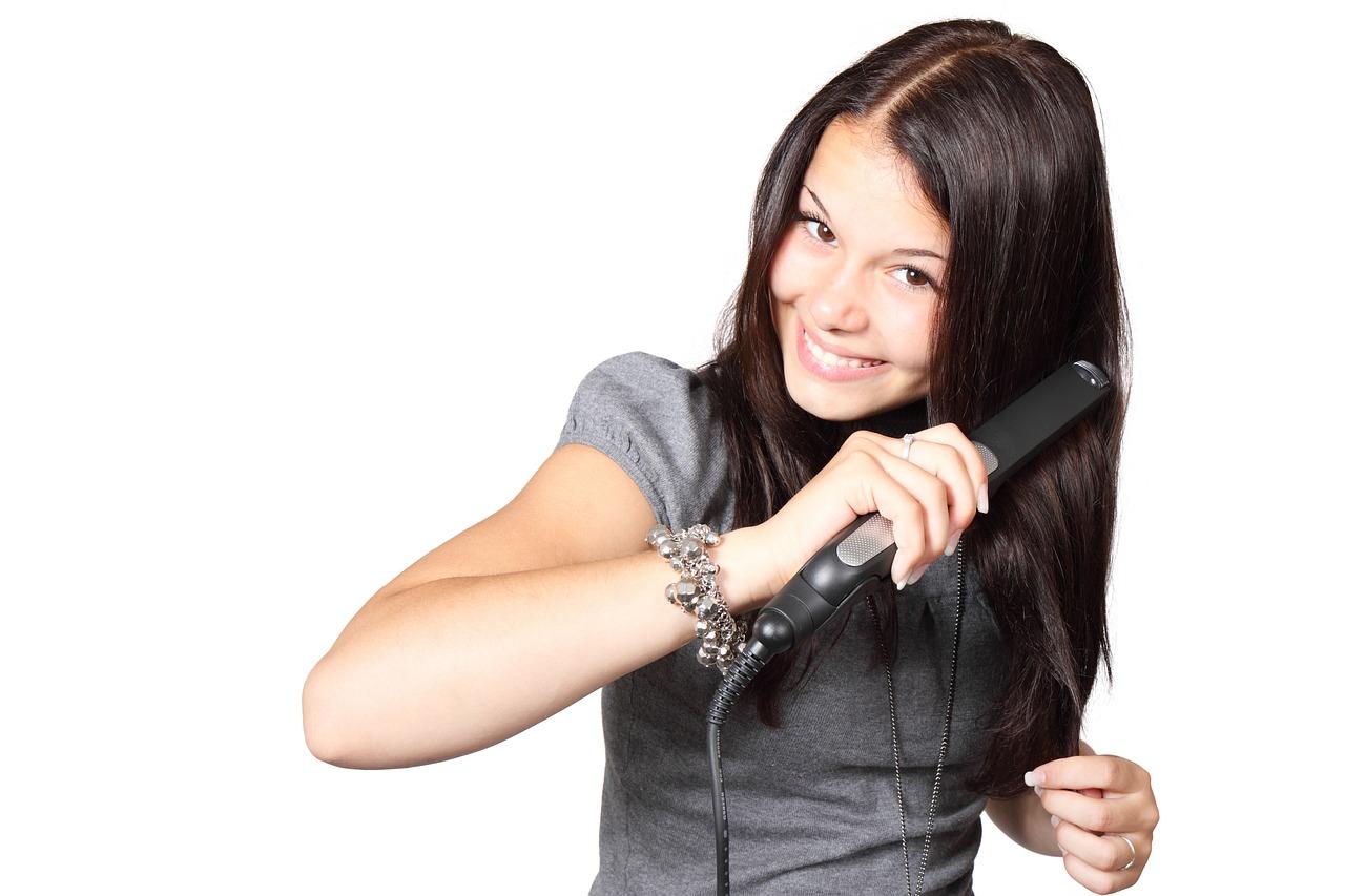 Jente retter håret med krølltang