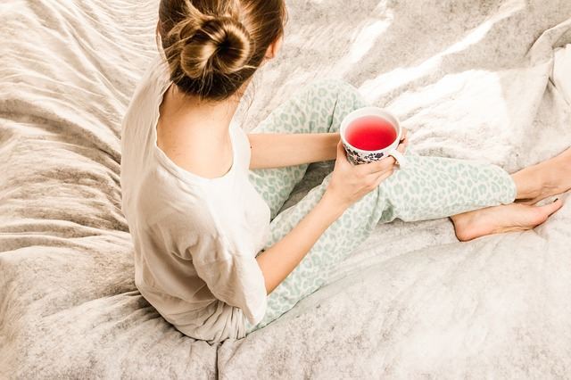 Sieviete ar tēju uz gultas